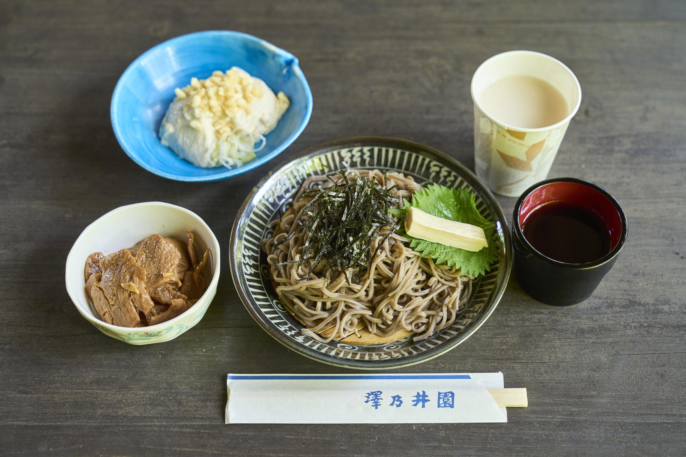 中央はざるそば。左の小鉢は大豆でつくった珍味「畑のお肉」、その上はおぼろ豆腐、カップには甘酒