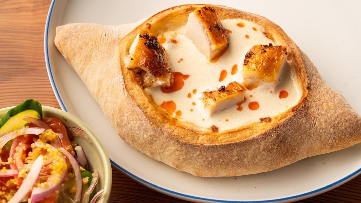 赤インゲン豆のペーストを入れて焼いたハチャプリに、郷土料理のシュクメルリを入れる Photo: courtesy of 8000Vintages Co.,LTD.