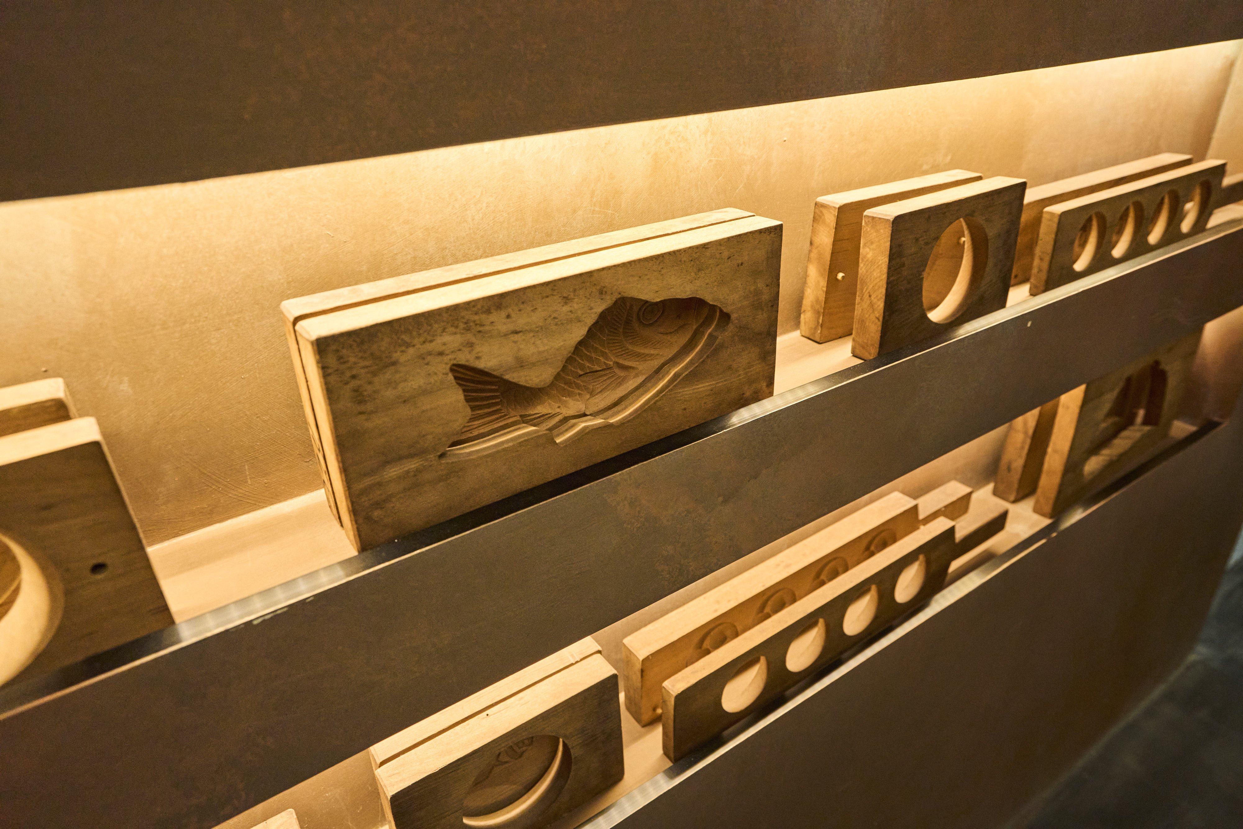 Traditional wooden wagashi molds passed down at Aoyama Beniya, displayed along the walls.